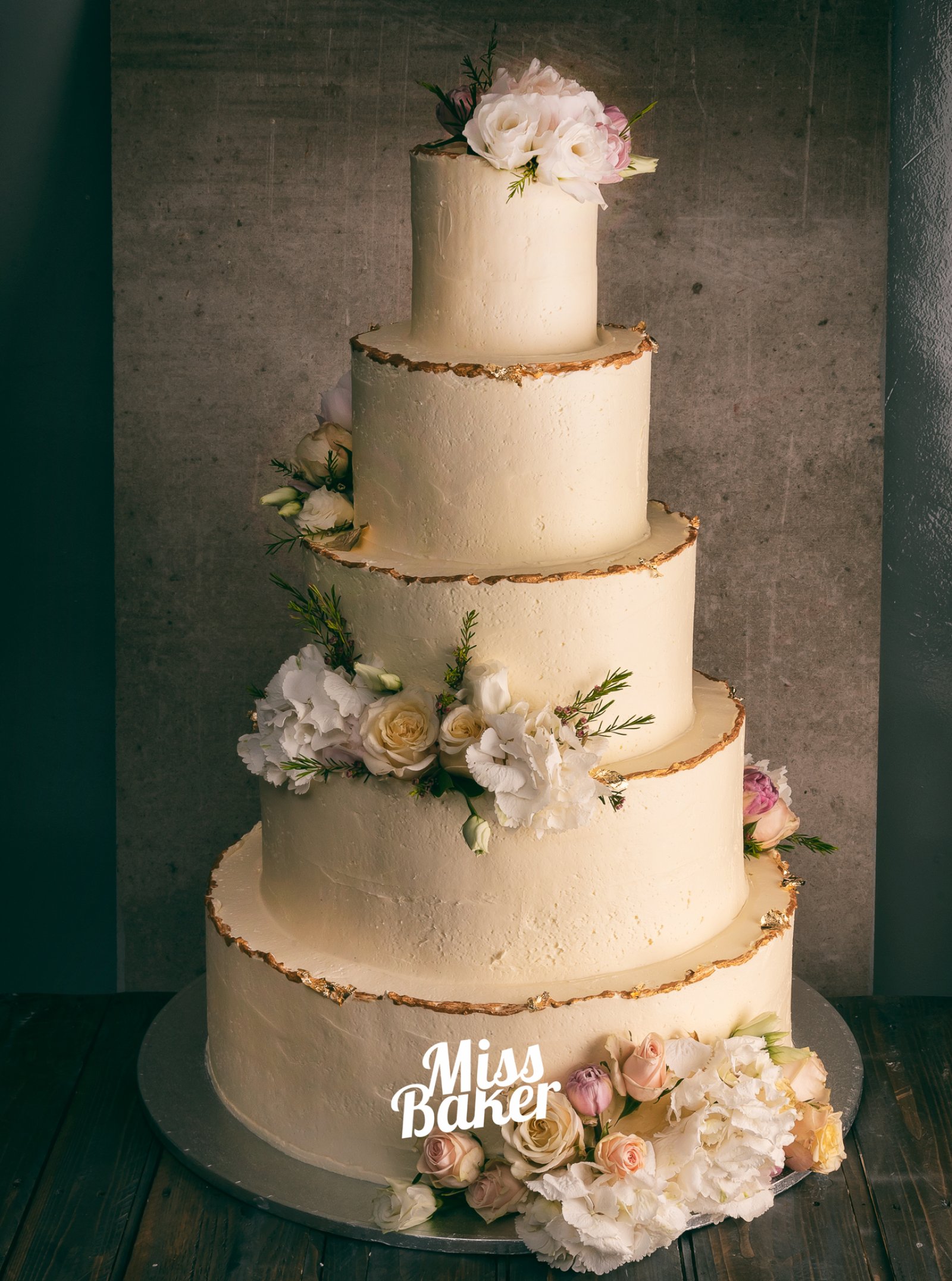 Torturi de nuntă de la Miss Baker — patru niveluri, margine aurie subțire, aranjament floral diagonal