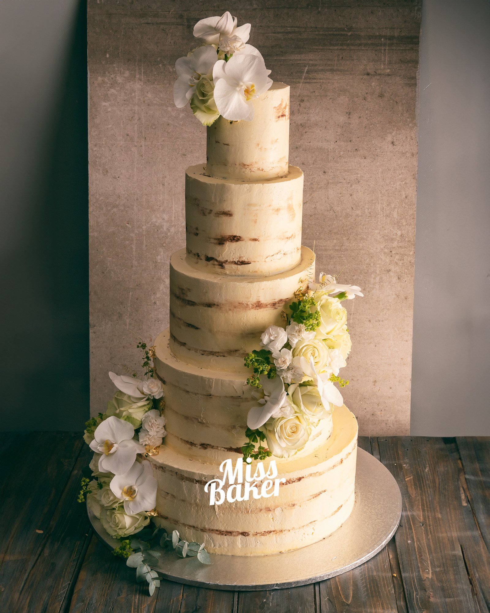 Torturi de nuntă de la Miss Baker — patru niveluri, aranjament floral lateral, flori naturale albe