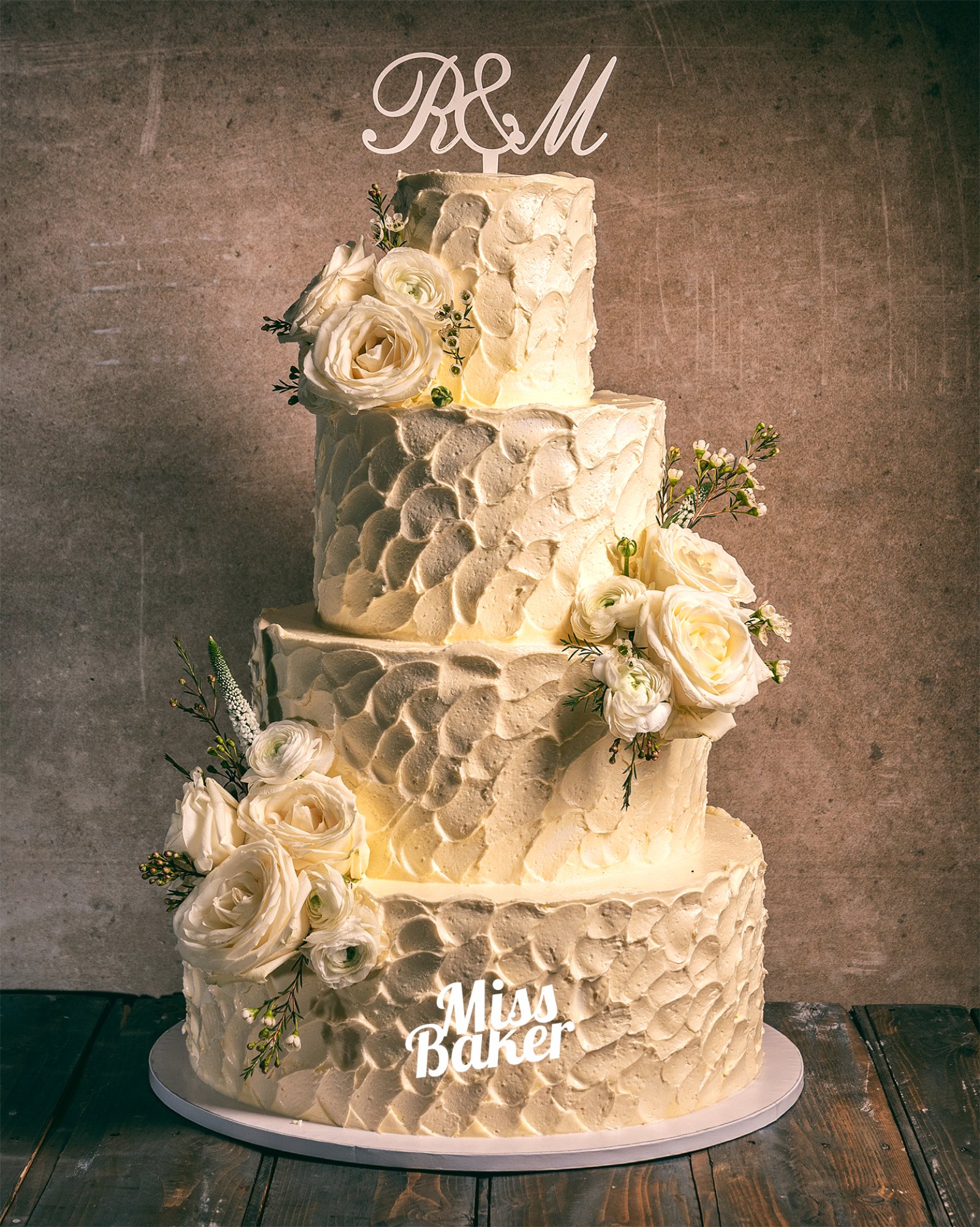 Torturi de nuntă de la Miss Baker — patru niveluri, textură solzi reliefată, aranjament floral lateral