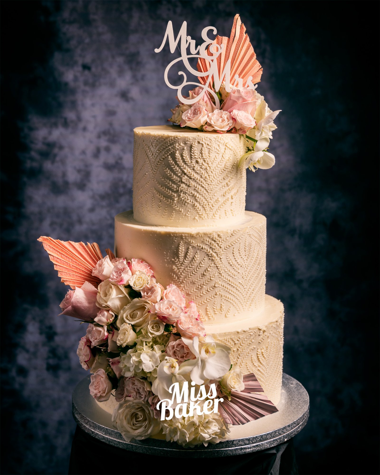 Torturi de nuntă de la Miss Baker — model dantelat crem, evantai roz texturat, aranjament flori naturale pastel