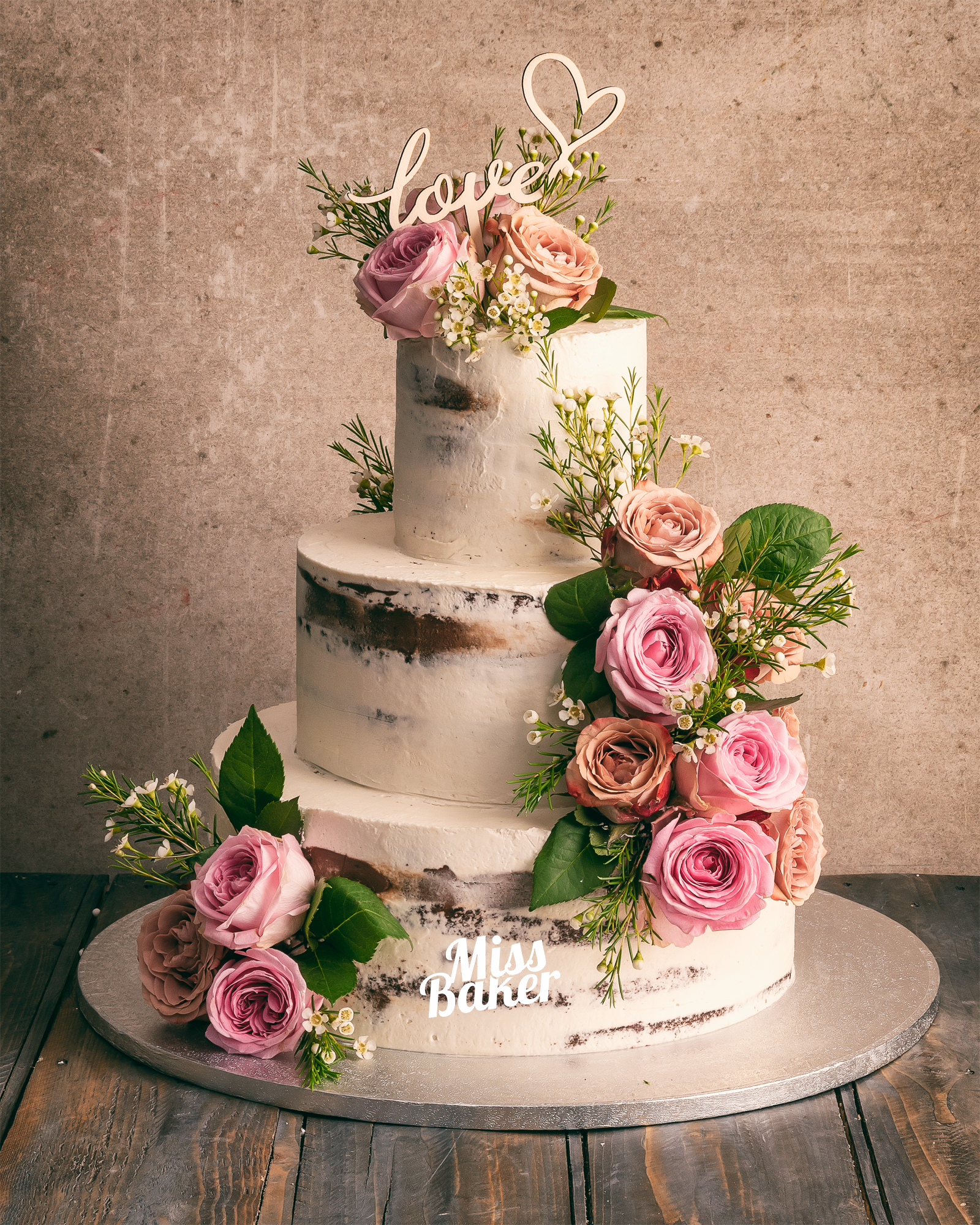 Torturi de nuntă de la Miss Baker — tort trei niveluri, aranjament floral lateral, bază rotundă